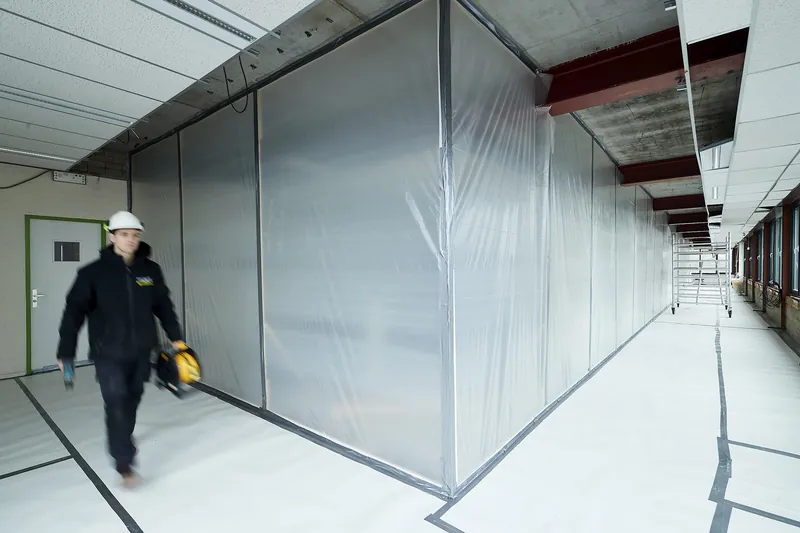 Medewerker loopt langs een hermetische zone in folie